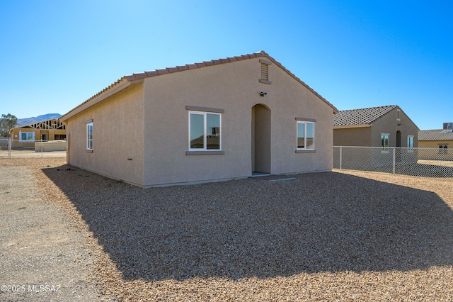 rear view of property with a fenced backyard, a tiled roof, and stucco siding