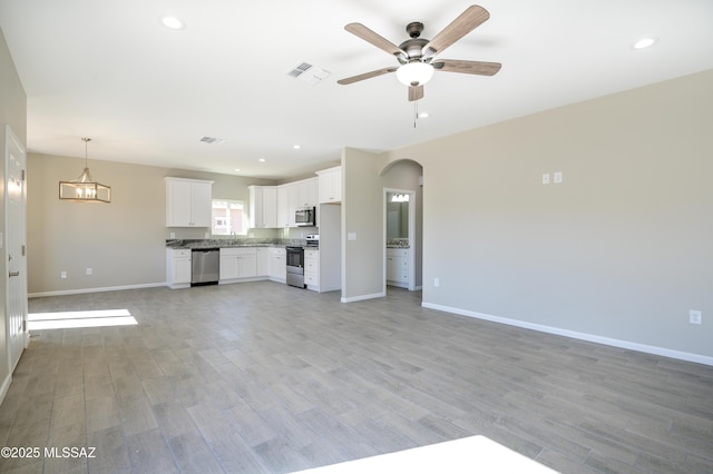 unfurnished living room with arched walkways, recessed lighting, a ceiling fan, visible vents, and light wood-style floors