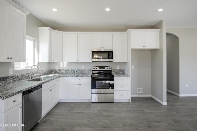 kitchen featuring appliances with stainless steel finishes, stone countertops, white cabinets, and a sink