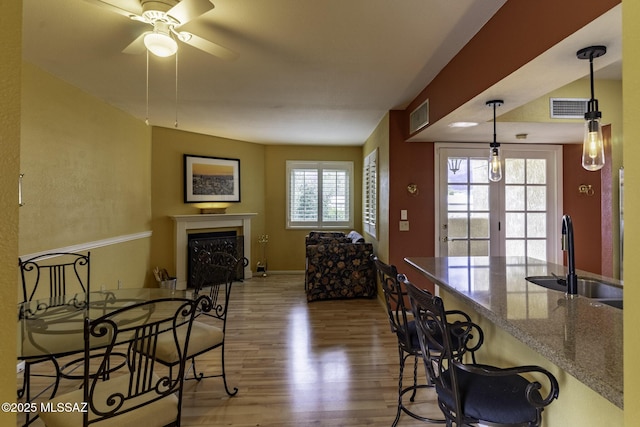 dining area featuring visible vents, a fireplace, baseboards, and wood finished floors