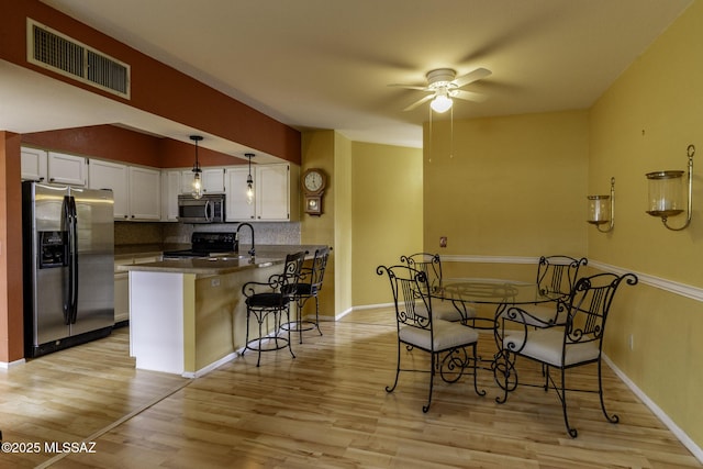 dining area featuring a ceiling fan, visible vents, light wood finished floors, and baseboards