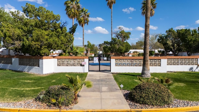 community / neighborhood sign featuring fence, a yard, and a gate