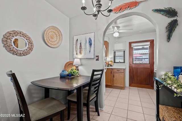 dining space with light tile patterned floors, arched walkways, and ceiling fan with notable chandelier