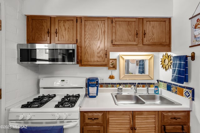 kitchen featuring stainless steel microwave, brown cabinets, white range with gas cooktop, and a sink