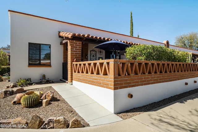 view of front facade featuring stucco siding, brick siding, and a tiled roof