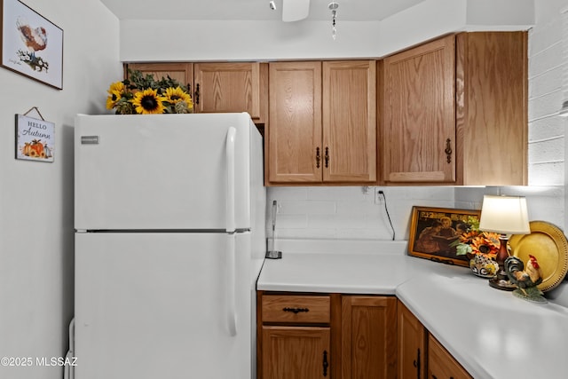 kitchen featuring tasteful backsplash, brown cabinetry, light countertops, and freestanding refrigerator