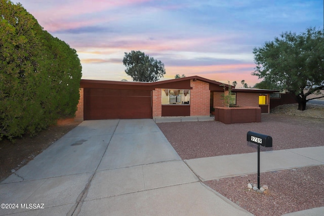 mid-century home featuring a garage, concrete driveway, and brick siding