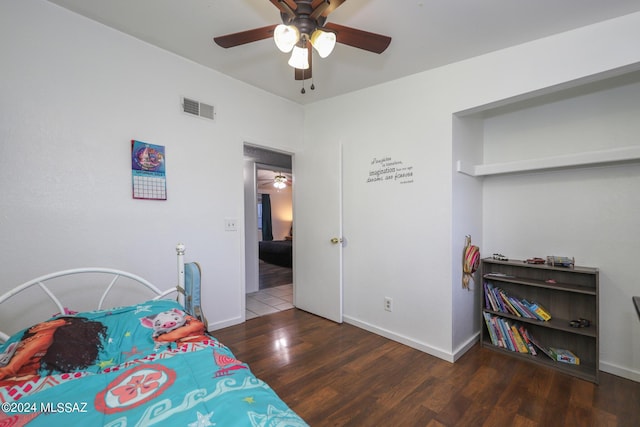 bedroom featuring a ceiling fan, wood finished floors, visible vents, and baseboards