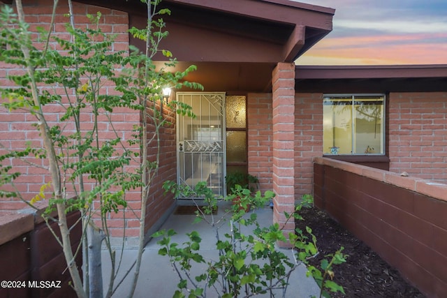 view of exterior entry featuring brick siding