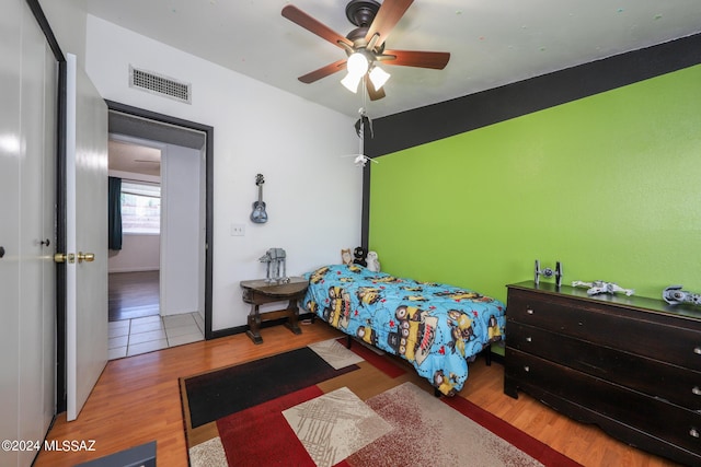 bedroom with baseboards, visible vents, ceiling fan, and wood finished floors