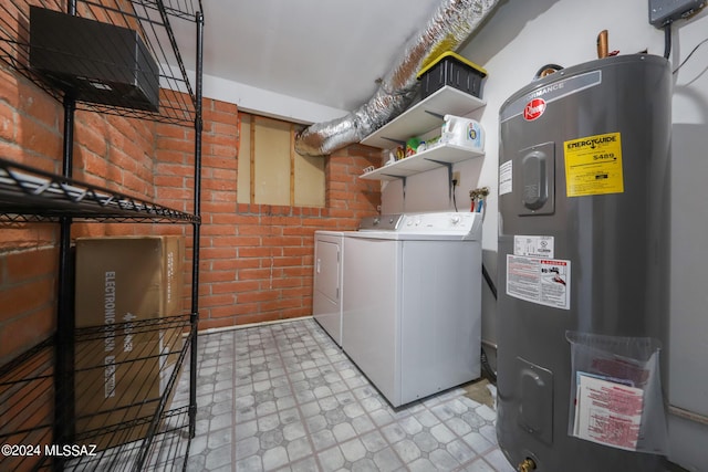 clothes washing area with light floors, brick wall, water heater, and washer and clothes dryer