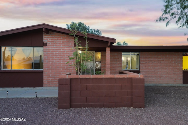 property exterior at dusk featuring brick siding