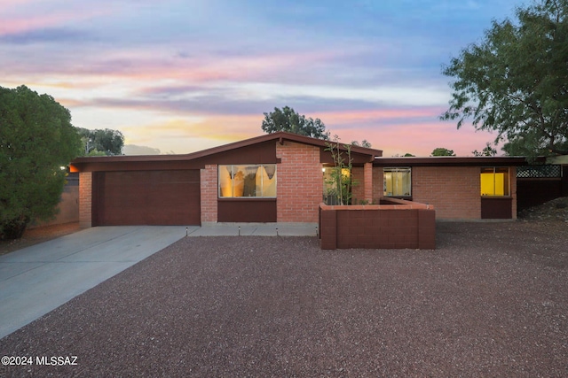 mid-century home featuring a garage, brick siding, and driveway