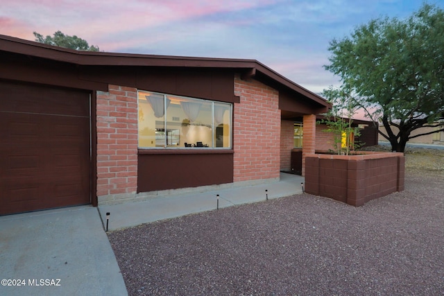 view of side of home featuring brick siding and an attached garage