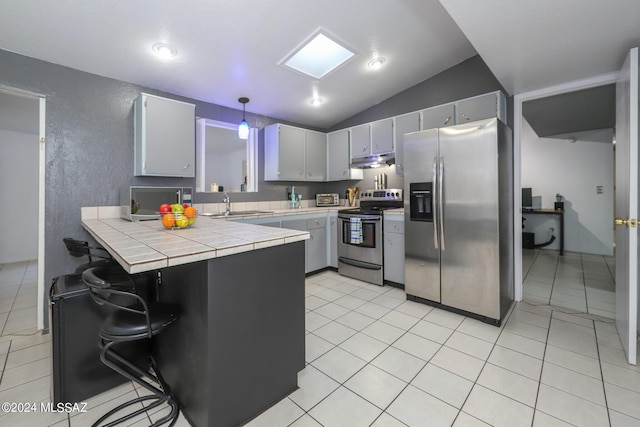 kitchen featuring tile countertops, under cabinet range hood, a peninsula, a sink, and appliances with stainless steel finishes