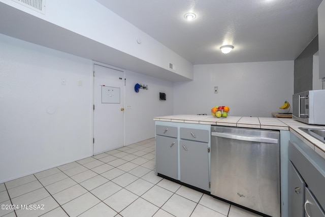 kitchen with tile countertops, light tile patterned floors, visible vents, gray cabinets, and dishwasher