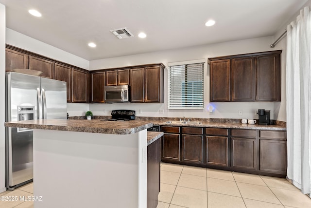 kitchen featuring visible vents, a center island, stainless steel appliances, dark brown cabinets, and a sink