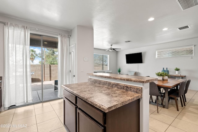 kitchen featuring light tile patterned floors, dark brown cabinets, visible vents, and a center island