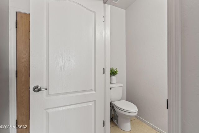 bathroom with baseboards, toilet, and tile patterned floors