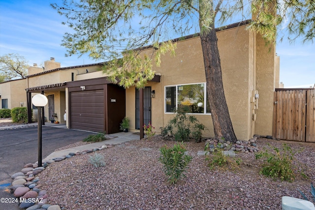 view of front of house featuring an attached garage, fence, aphalt driveway, and stucco siding