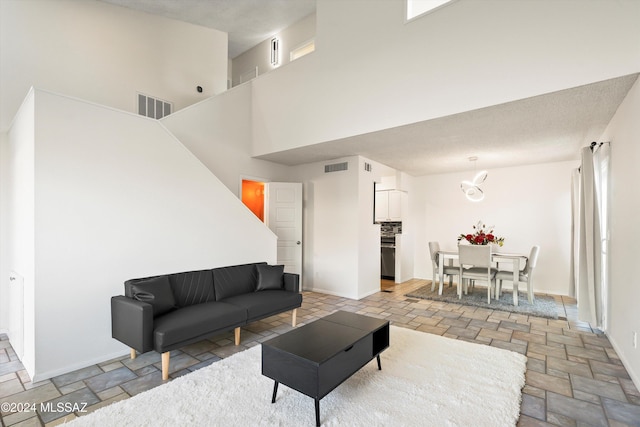 living area featuring baseboards, visible vents, and stone tile floors