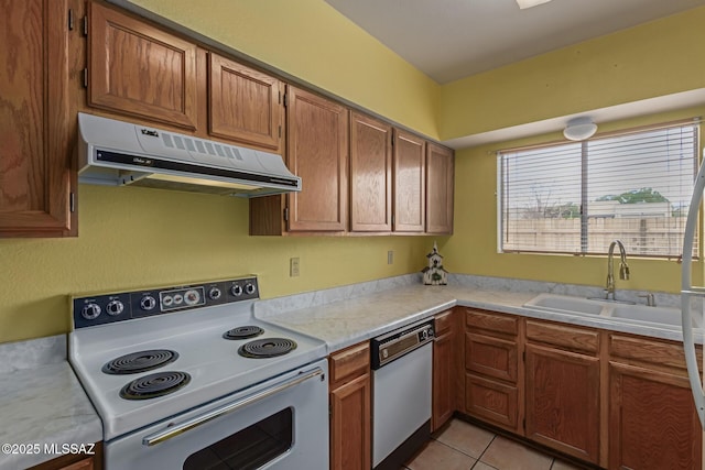 kitchen with light tile patterned floors, white appliances, light countertops, under cabinet range hood, and a sink