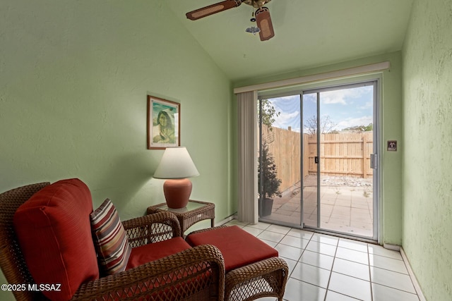 sitting room with lofted ceiling, light tile patterned flooring, a ceiling fan, and a textured wall