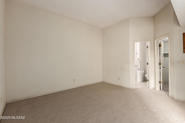 unfurnished room featuring carpet and vaulted ceiling