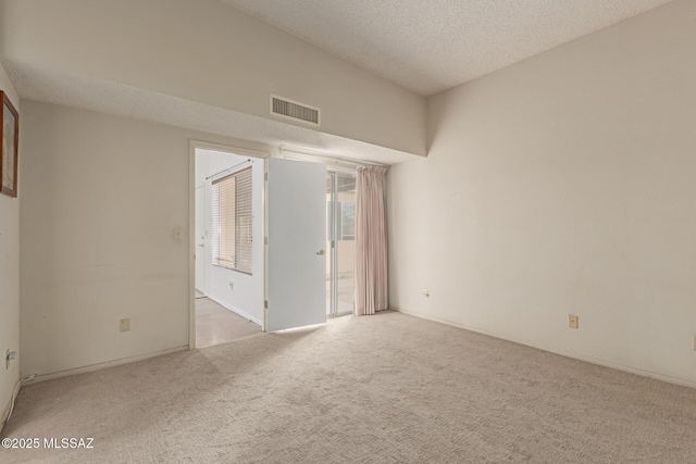 carpeted empty room with visible vents and a textured ceiling