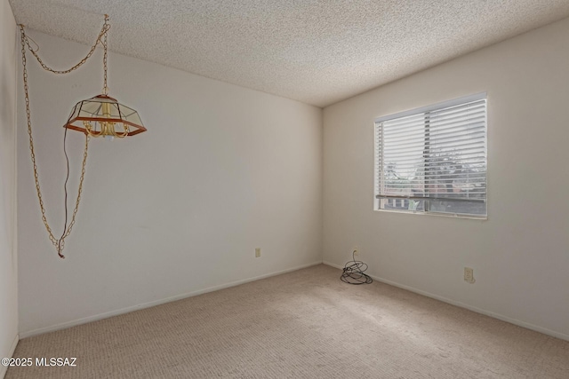 empty room with carpet, baseboards, and a textured ceiling