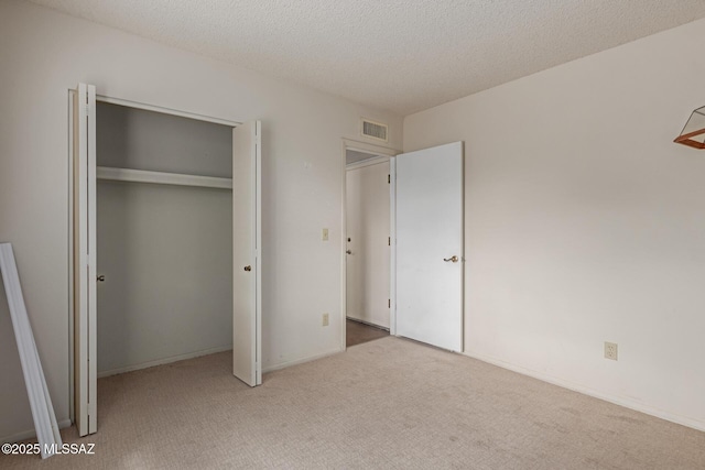 unfurnished bedroom with carpet floors, a closet, visible vents, and a textured ceiling