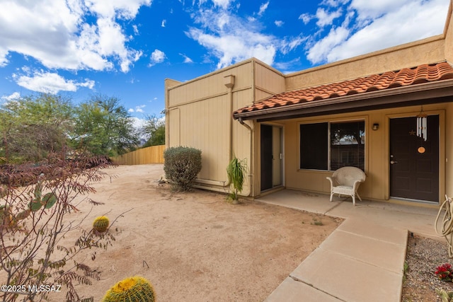 back of house with a patio area, a tile roof, and fence