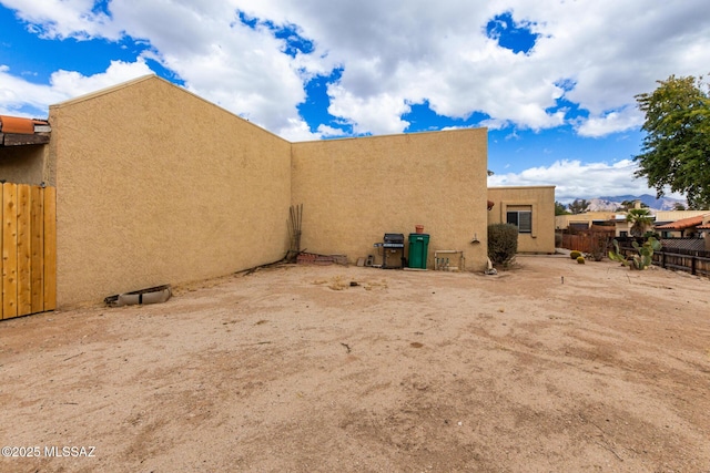 back of house with fence and stucco siding