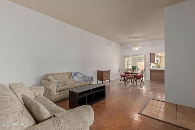 living room featuring ceiling fan, a textured ceiling, and baseboards