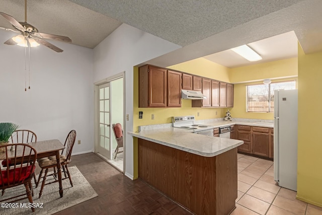 kitchen with a textured ceiling, under cabinet range hood, a peninsula, white appliances, and light countertops