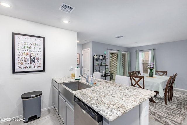 kitchen featuring visible vents, dishwasher, light stone countertops, and a sink