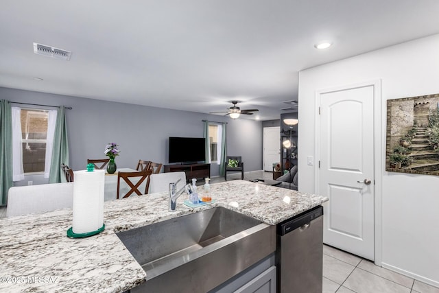 kitchen with light tile patterned floors, light stone countertops, visible vents, a sink, and dishwasher