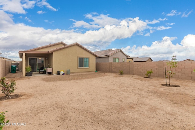 back of house with stucco siding, a patio area, a fenced backyard, and a tile roof