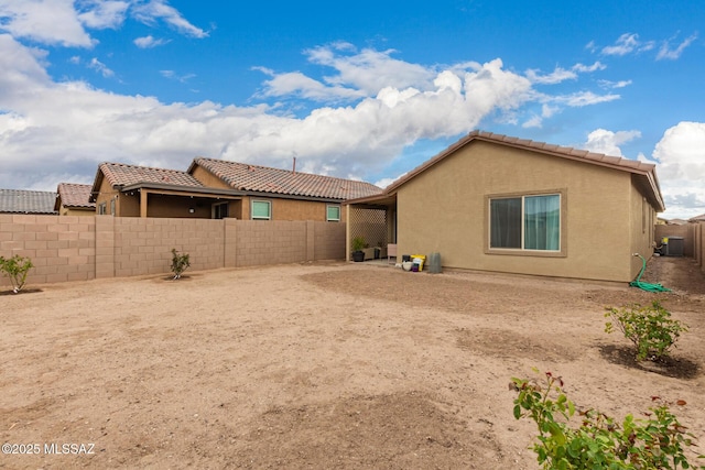 rear view of house with a tiled roof, cooling unit, a fenced backyard, and stucco siding