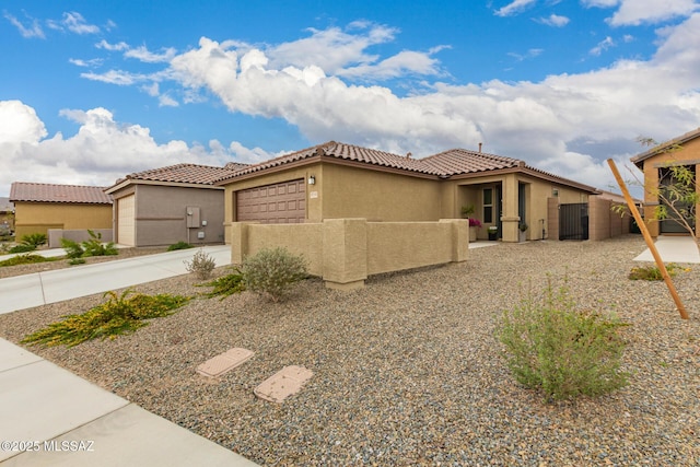 mediterranean / spanish-style house with fence, driveway, stucco siding, a garage, and a tiled roof