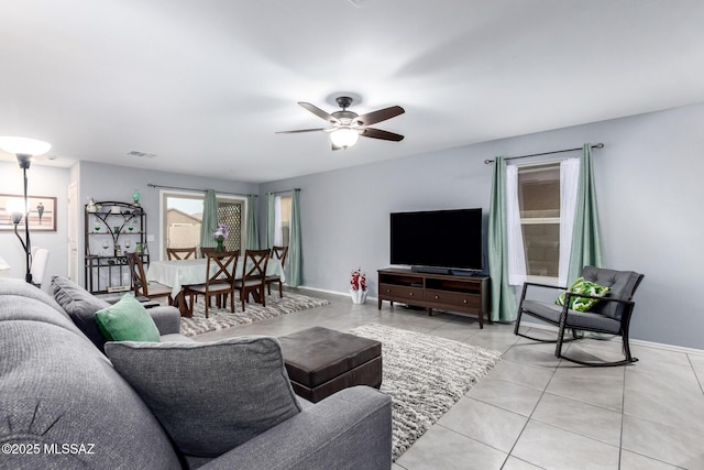 living area featuring light tile patterned floors, visible vents, baseboards, and ceiling fan