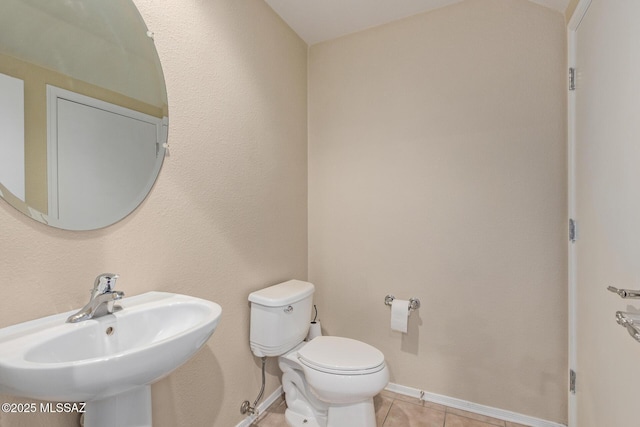 bathroom with toilet, baseboards, a sink, and tile patterned floors