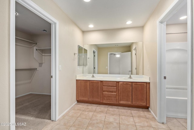 bathroom featuring double vanity, tile patterned flooring, a spacious closet, and a sink