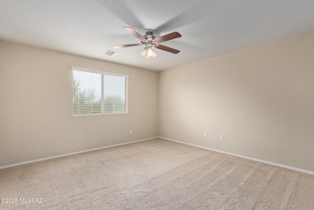 spare room with light carpet, ceiling fan, visible vents, and baseboards