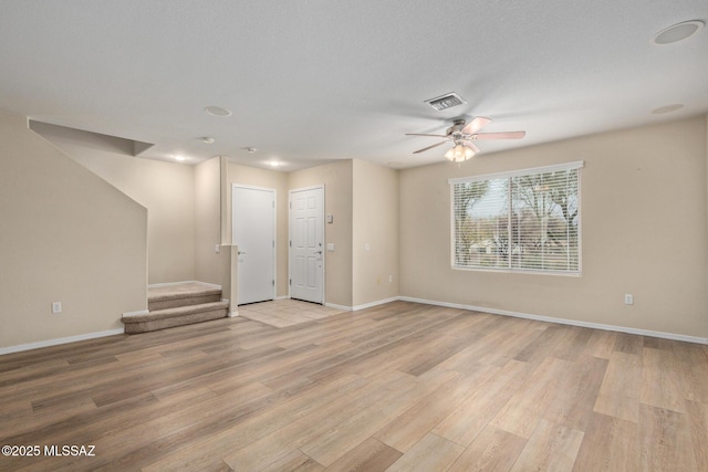 unfurnished living room featuring light wood-style flooring, visible vents, stairway, and baseboards