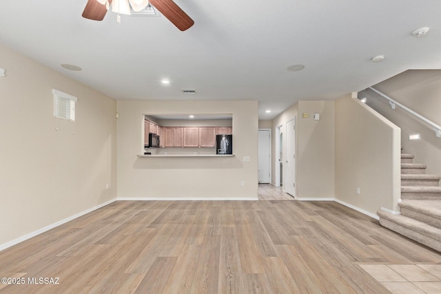 unfurnished living room featuring light wood-style floors, baseboards, stairs, and visible vents