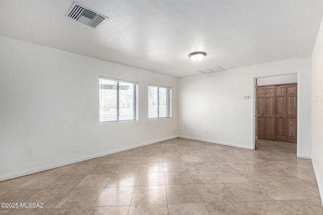 unfurnished room featuring baseboards and visible vents