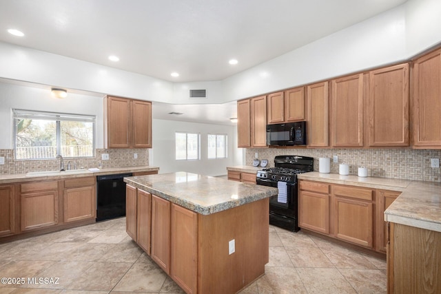 kitchen featuring black appliances, decorative backsplash, a sink, and a center island