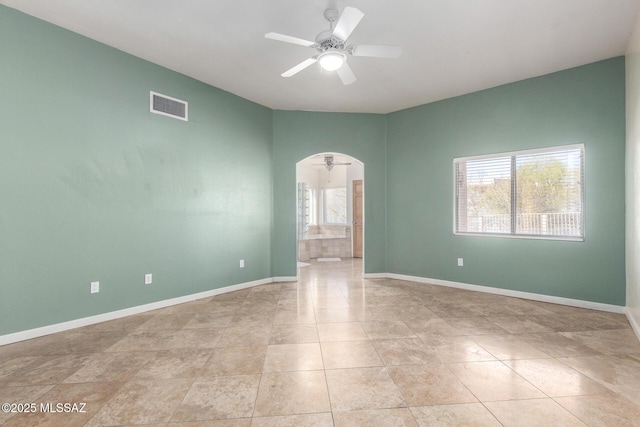 unfurnished room featuring baseboards, visible vents, arched walkways, a ceiling fan, and light tile patterned flooring