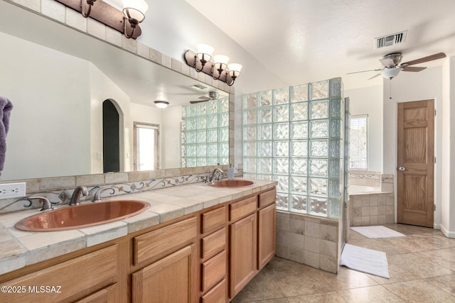 bathroom featuring a ceiling fan, visible vents, a garden tub, and a sink